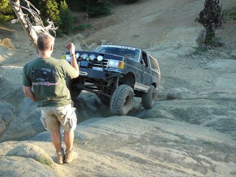 1991 Ford Bronco - A person watches a 1991 Ford Bronco navigate a challenging rocky off-road course.