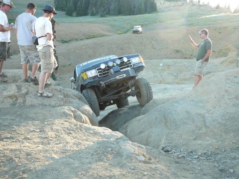 1991 Ford Bronco - A modified 1991 Ford Bronco tackles a challenging rocky obstacle with spectators watching.