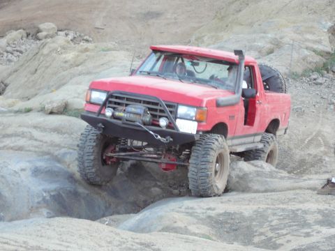 1991 Ford Bronco - This modified SUV is tackling a challenging off-road course with steep inclines and rocky terrain.