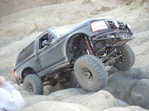 1991 Ford Bronco - This modified SUV navigates a rocky terrain with its suspension clearly visible.