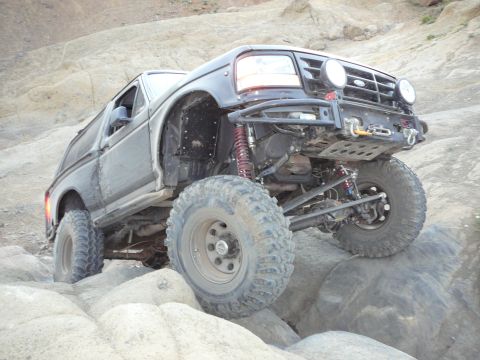 1991 Ford Bronco - This heavily modified Ford Bronco is navigating a rocky off-road course, its impressive suspension and tire clearance.