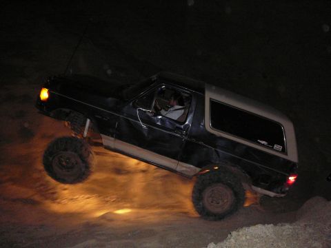 1991 Ford Bronco - Ford Bronco navigates rough terrain at night, with one wheel off the ground.