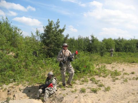 2003 Ford Crown Victoria - People in camouflage gear and holding rifles stand in a wooded area under a cloudy sky.
