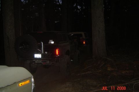 1978 Ford Bronco - A black Ford Bronco is parked in a wooded area at night, with another vehicle visible behind it.