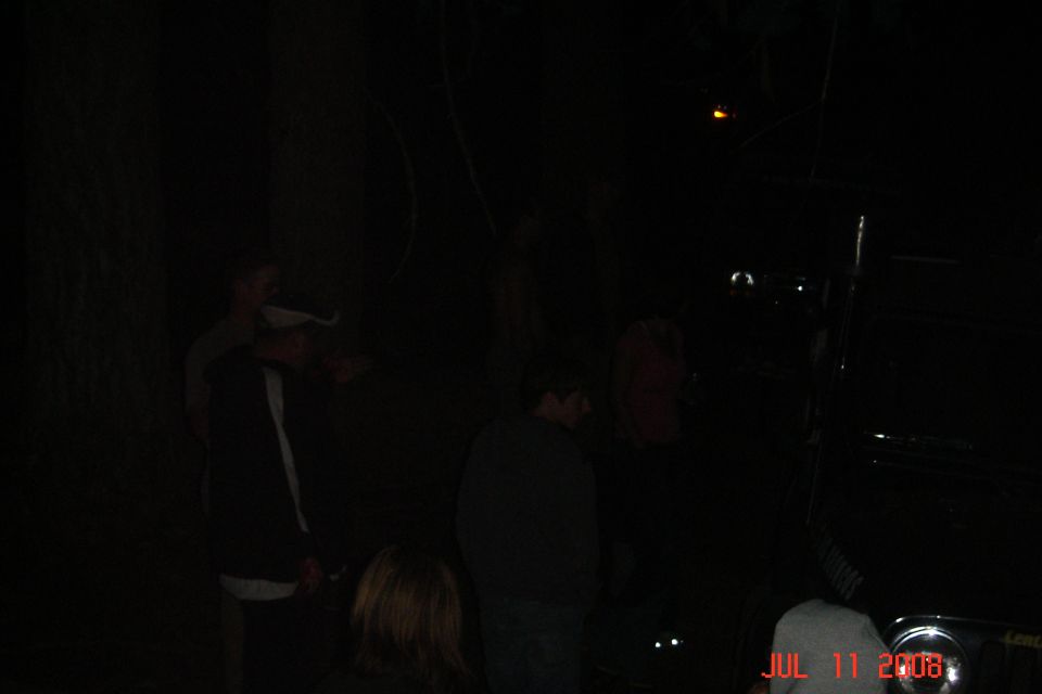 people standing near a dark vehicle at night, with a date stamp of JUL 11 2008 visible on the lower right