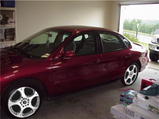 1998 Ford Taurus - A red 1998 Ford Taurus is parked inside a garage.
