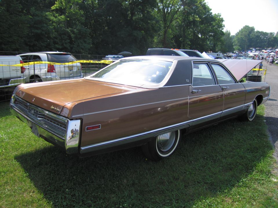 Brown sedan with a black vinyl roof parked on grass, hood open, chrome trim, whitewall tires