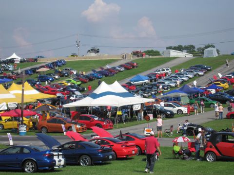 2001 Ford Crown Victoria - A large gathering of vehicles is displayed under tents and in open areas on a sunny day.