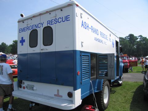 2001 Ford Crown Victoria - A vintage emergency rescue truck is parked outdoors with other vehicles and people in the background.