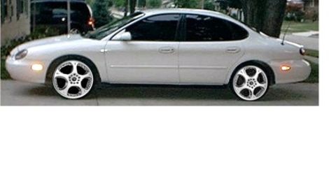 1998 Ford Taurus - A white sedan is shown from the side, custom wheels and tinted windows.