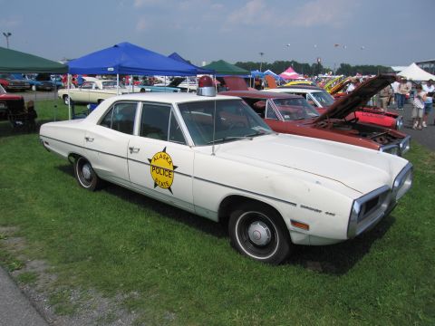 2001 Ford Crown Victoria - White 1970 Dodge Polara police car with Alaska State Police decal on door is displayed at a car show.