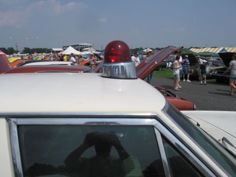 2001 Ford Crown Victoria - A car show features various vehicles under a bright, partly cloudy sky.