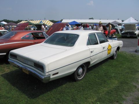 2001 Ford Crown Victoria - This 1969 Dodge Polara police car is displayed at an outdoor event with other vehicles and tents in the background.