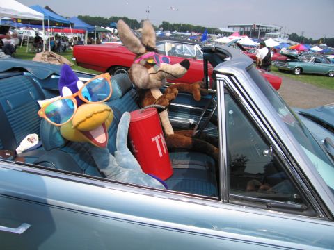 2001 Ford Crown Victoria - Plush toys dressed in sunglasses are seated in a vintage convertible at an outdoor event.