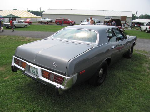 2001 Ford Crown Victoria - Rear view of a gray sedan parked on grass with other vehicles and tents in the background.