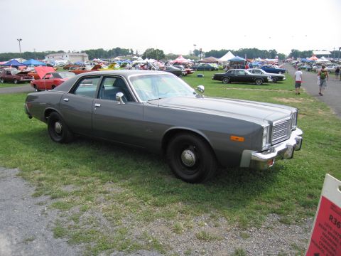 2001 Ford Crown Victoria - A 1977 Dodge Monaco sedan is displayed at an outdoor event with other vehicles and tents in the background.