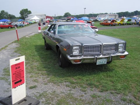 2001 Ford Crown Victoria - A gray sedan is parked on the grass at an outdoor event with other vehicles and tents in the background.