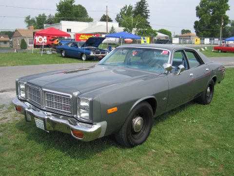 2001 Ford Crown Victoria - A gray sedan is parked on a grassy field with other vehicles and tents in the background.