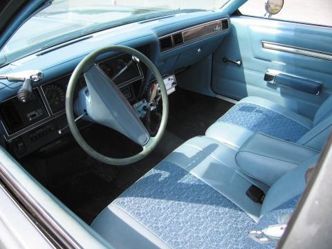 2001 Ford Crown Victoria - The interior of a vintage car shows light blue upholstery and a classic dashboard layout.