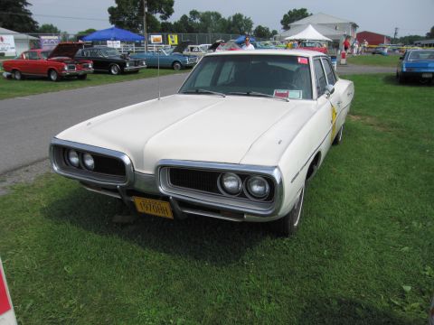 2001 Ford Crown Victoria - White 1970 Dodge Coronet sedan parked on grass at an outdoor car show.