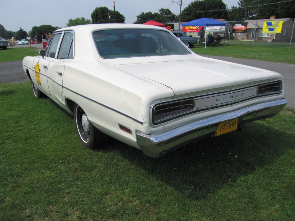 Rear view of a white 1970 Dodge sedan with a yellow license plate reading 1970HH and police-style door markings
