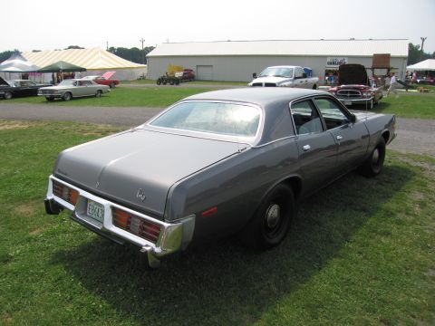 2001 Ford Crown Victoria - A gray sedan is parked on a grassy field with other vehicles and tents in the background.