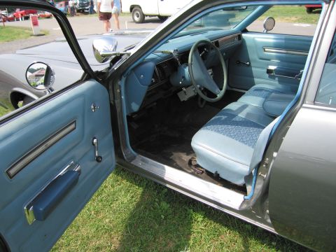 2001 Ford Crown Victoria - The interior of a classic car features light blue upholstery and dashboard details, with the driver's side door open.