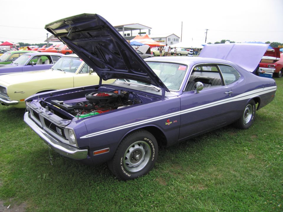 purple Dodge Dart with hood and trunk open, parked on grass next to a yellow car