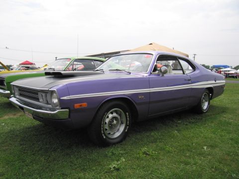 2001 Ford Crown Victoria - A purple Dodge Dart with a white stripe and hood scoop is parked on grass next to another car.
