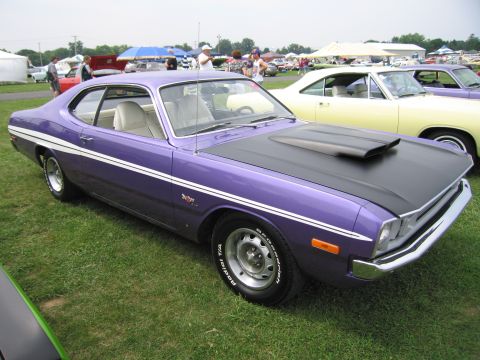 2001 Ford Crown Victoria - A purple 1973 Dodge Dart Swinger is displayed at a car show with other vehicles in the background.