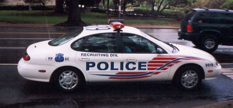 1998 Ford Taurus - This 1998 Ford Taurus police car features "RECRUITING DIV." text and a distinctive stripe pattern on its side.