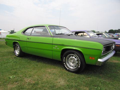 2001 Ford Crown Victoria - A green 1970 Plymouth Duster is displayed outdoors with other vehicles in the background.