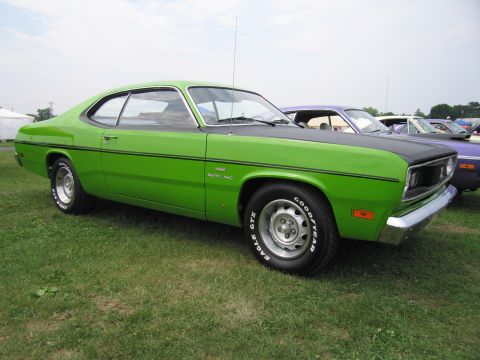 2001 Ford Crown Victoria - A bright green Duster 340 sits on a grassy field next to other vehicles.