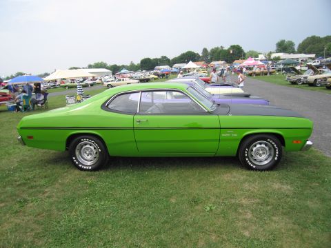 2001 Ford Crown Victoria - A bright green muscle car with a black hood is parked on a grassy field alongside other vehicles.