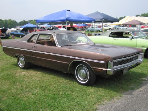 2001 Ford Crown Victoria - A brown coupe sits on a grassy field at an outdoor event with tents and other vehicles visible.