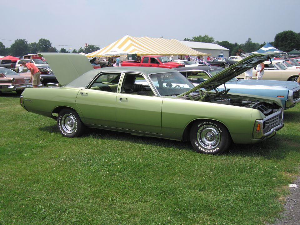 Green Dodge four-door sedan with hood up at a car show