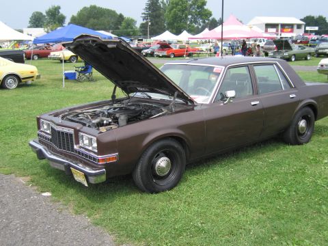 2001 Ford Crown Victoria - Photo of a brown four-door Dodge sedan with its hood raised at an outdoor car show.