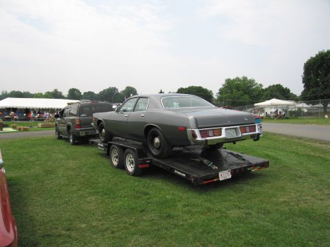 2001 Ford Crown Victoria - Photo of a dark four-door sedan loaded on a trailer being towed at a car show field.