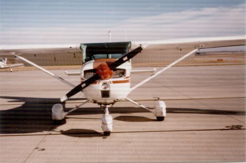 1998 Ford Taurus - A small single-engine airplane is parked on the tarmac, with another aircraft in the distance under a clear sky.