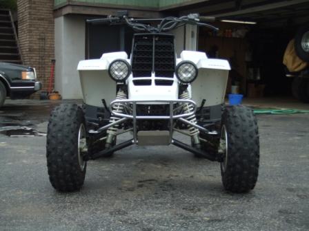 1996 Ford Bronco - Front view of a white ATV with large knobby tires parked on an asphalt surface. The ATV has a black grille, two round headlights, and chrom…
