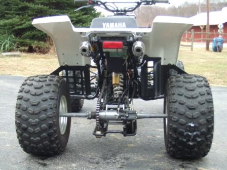 1996 Ford Bronco - The rear view of a white Yamaha ATV is shown, featuring large knobby tires, dual exhaust pipes, and a red taillight.