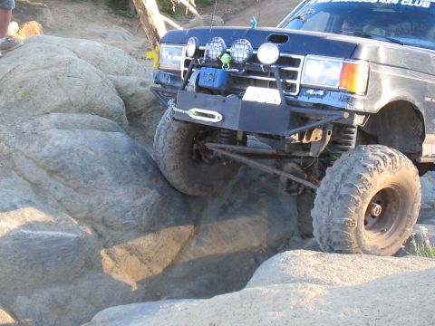 1989 Ford Bronco - This modified SUV is navigating a challenging rocky terrain, its off-road capabilities.