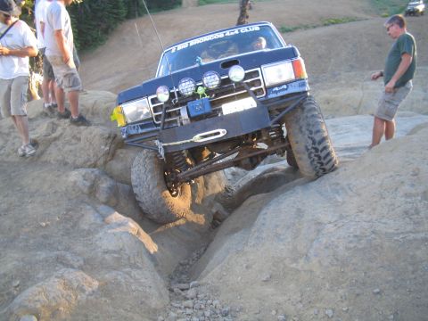 1989 Ford Bronco - A modified Ford Bronco navigates a rocky obstacle during an off-road event.