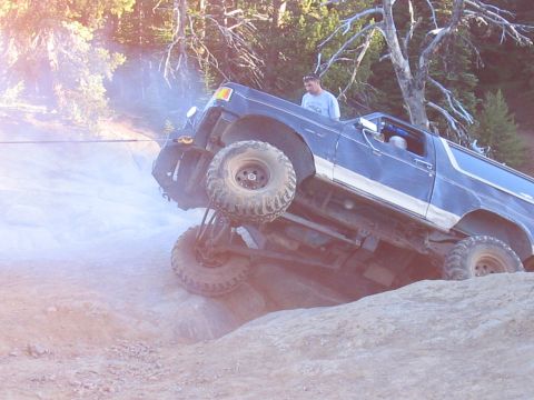 1989 Ford Bronco - This SUV is navigating a challenging off-road terrain, with one side significantly higher than the other.