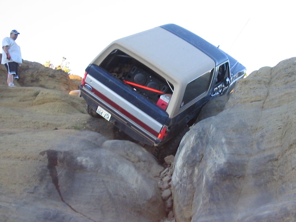 Dark blue and tan Ford Bronco navigating a rocky trail, rear view
