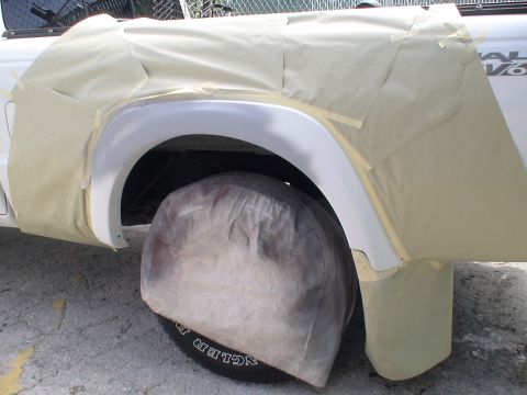 1993 Ford C-350 (Centurion Conversions) - A white pickup truck's fender and wheel are covered in masking tape, preparing for paint work. The "DUAL V6" badge is partially visible.