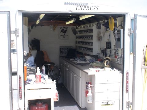 1993 Ford C-350 (Centurion Conversions) - The interior of a trailer is organized with storage shelves, a workbench, and cabinets, with the word 'EXPRESS' visible on the exterior.