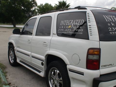 1993 Ford C-350 (Centurion Conversions) - A white SUV is parked outdoors, displaying business advertising on its windows.