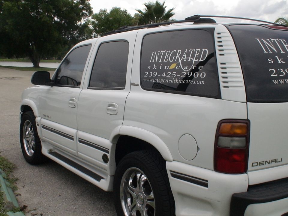 White SUV with tinted windows and 'Integrated Skincare' decals on the rear side window