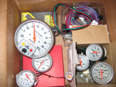 1992 Ford Mustang - A collection of automotive gauges and associated wiring are organized within a cardboard box, suggesting they are parts for a vehicle.